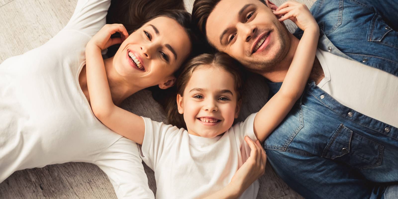Family smiling while girl having her hand on neck line of other two