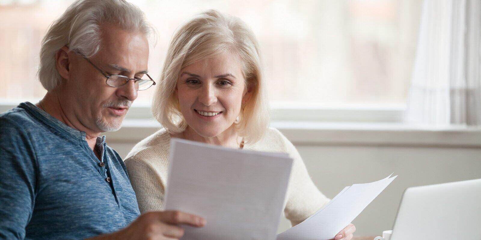 middle aged couple holding reading good news in document