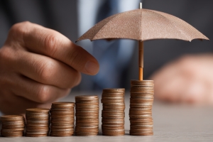 Hand Holding Umbrella Over Coin Stacks Representing Investment Protection
