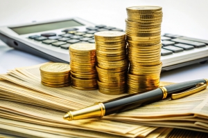 Stack of Cash and Gold Coins on A Pile of Contracts with Pen