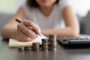 Woman Behind Stack of Coins Comparing Growth of Retirement Plans